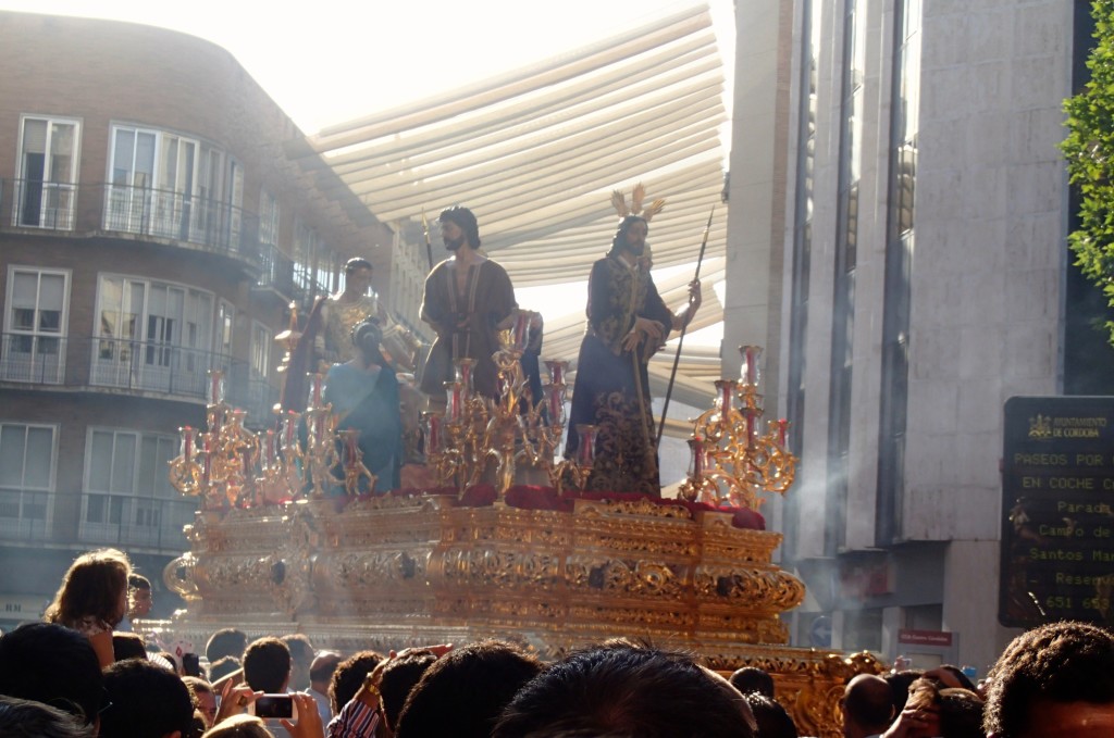 The float moves through the crowd of people and incense